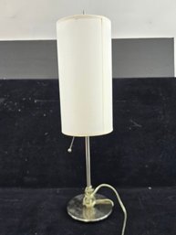 Modern Brushed Metal Stick Table Lamp Featuring A Tall Cylindrical Fabric Shade And Pull Chain Switch