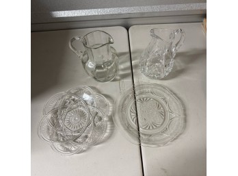 Two Patterned Glass Pitchers And Two Clear Serving Plates