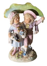 PORCELAIN FIGURINE OF CHILDREN UNDER A LARGE LEAF