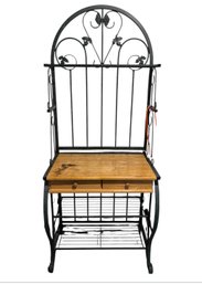 Black Metal And Wood Baker's Rack With A Scrollwork Design, Two Wooden Drawers, And A Lower Wire Shelf.