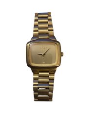 Nixon The Player Gold Watch, A Quartz Analog Watch With A Diamond Detail At The 6 O'clock Position.