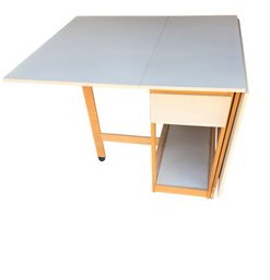 Drop-leaf Folding Kitchen Table With Storage Cabinets, Likely Made Of Wood And A Light-colored Top.