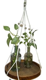 Handmade Macrame Plant Hanger With A Wood Base For Displaying Plants In Glass Bottles.