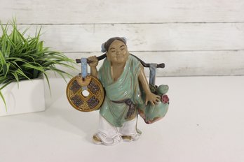 A Chinese Shiwan Mudman Figurine Depicting A Person Carrying Objects On A Yoke.