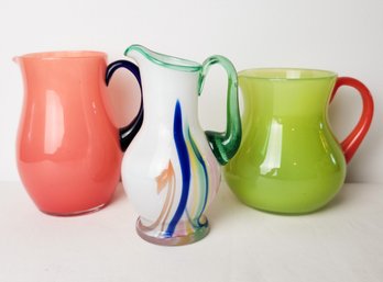 Three Colorful Glass Pitchers