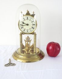 A Vintage Brass Anniversary Clock With Key Under Glass Dome