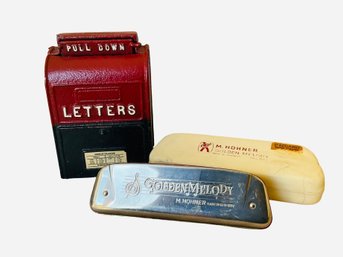 The Image Features A Cast Iron US Mailbox Coin Bank And A M. Hohner Golden Melody Harmonica