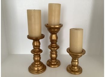 Three  Gold Tone Candlestick Holders In Different Sizes. Candles Included