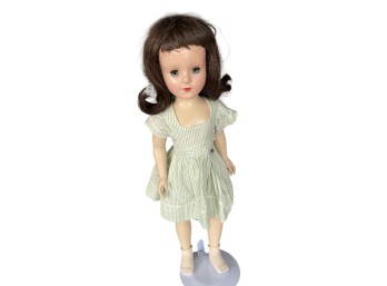 Vintage Hard Plastic Girl Doll With Sleep Eyes, Brunette Wig, And Green Striped Dress On Stand