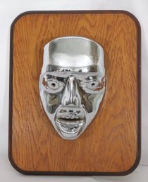 A Unique Vintage Silver Metal Face Mask On Oak Wood Panel.