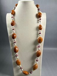 Beaded Necklace With Oval Brown Seeds And Smaller White And Purplish Beads.