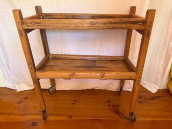 Rustic Two-tiered Wooden Trolley Features Prominent Pine Wood Grain And Small Wheels