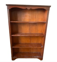 A Vintage Wooden Four-shelf Bookcase With Decorative Top And Fluted Sides
