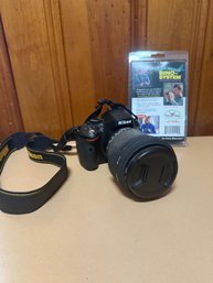 Nikon D5100 DSLR Camera With An Attached Lens And Neck Strap