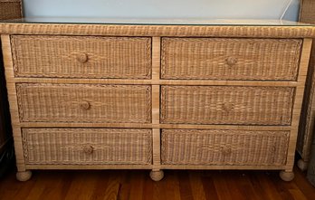 A Six-drawer Wicker Dresser With A Glass Top And Braided Wicker Pulls