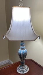 A Distressed Blue And White Ceramic Table Lamp With A Decorative Finial