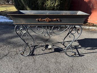 Ornate Wrought Iron Planter With Gilded Decorative Element On A Scrollwork Stand