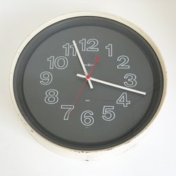 Round Analog Wall Clock With A Dark Grey Face. Howard Miller. Quartz. 13.50' In Diameter. Bold Outlined Number