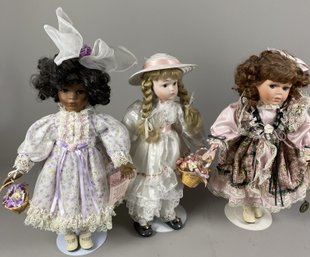 Three Porcelain Dolls In Old Fashioned Clothes Including A Collectible Memories Doll On Metal Stands