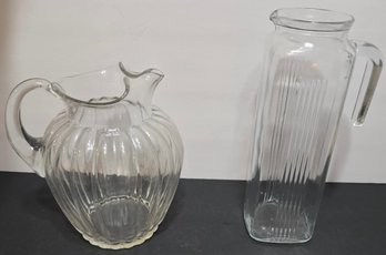 Two Different Styles Of Ribbed Glass Pitchers Or Jugs