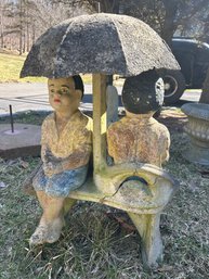 Yard Ornament Of Two Seated Figures Under Umbrella