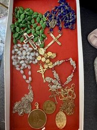 A Collection Of Religious Rosaries And Medals