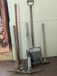 Lot Of Misc Long Handle Tools Including Pick Axes, A Sledge Hammer, A Tamper, Etc...