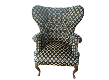 Wingback Chair With Dark Wood Legs And A Black And Gold Patterned Fabric.