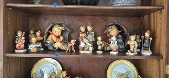 Collection Of Hummel Figurines Including Children With Umbrellas, Musicians, And Animals.