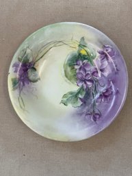 Antique Handpainted Porcelain Plate Featuring A Design Of Purple Violets Against A Soft Yellow And Green