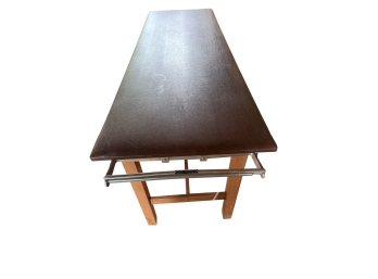 Rectangular Wooden Medi Table Features A Dark Brown Finished Top And A Metal Rail Attachment On The Front Edge