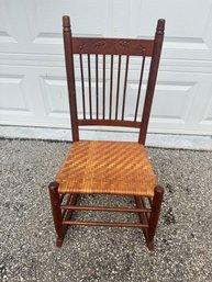 Antique Wooden Rocking Chair With Woven Seat And Carved Decorative Backrest.