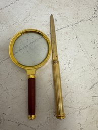 Vintage-style Handheld Magnifying Glass With A Gold-tone Frame And A Red Or Rosewood-colored Handle, Shown Alo