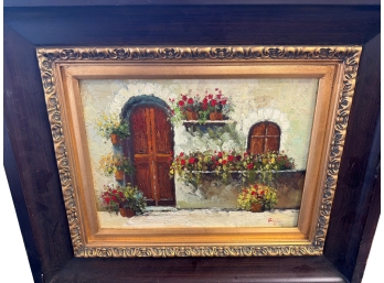 Framed Landscape Painting Depicting A Rustic European Cottage Scene With Potted Flowers
