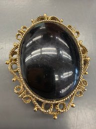 Vintage Brooch Features A Large Glossy Black Stone Set Within An Ornate, Gold-tone Filigree Border