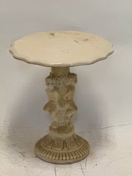 Vintage-style Side Table Or Plant Stand Featuring A Round, White Top And A Base Sculpted With Cherub Figurines