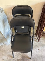 Set Of Four Classic Black Vinyl-padded Metal Folding Chairs Featuring A Sturdy Tubular Steel Frame And A Compa