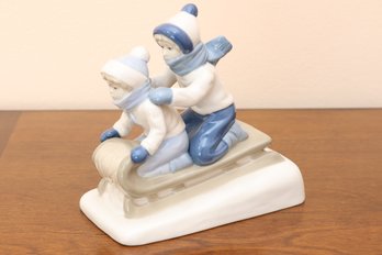 Porcelain Figurine: Two Children Sledding In Winter Attire
