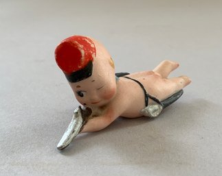 3' Long Kewpie, With Molded & Red Painted Hat With Black Brim, Prone With Rifle And Ammunition Bag