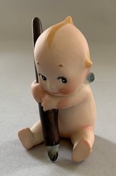 2  Kewpie Seated Holding A Dark Brown Pen